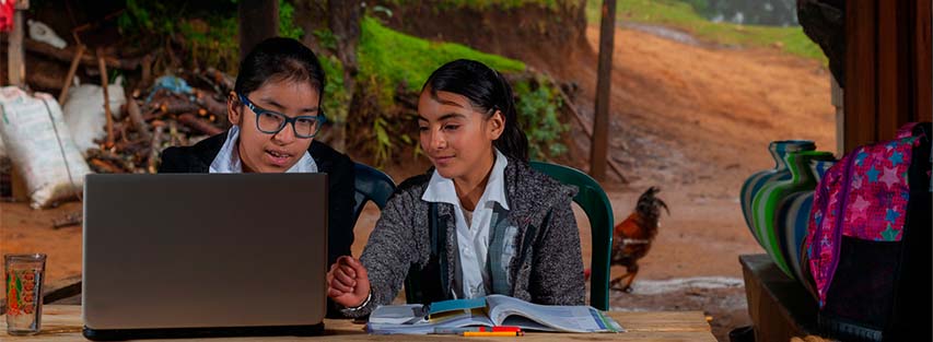 dos niñas haciendo la tarea en una computadora usando internet satelital